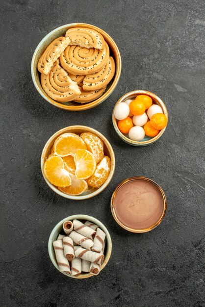 Vista superior de galletas dulces con caramelos sobre fondo gris oscuro