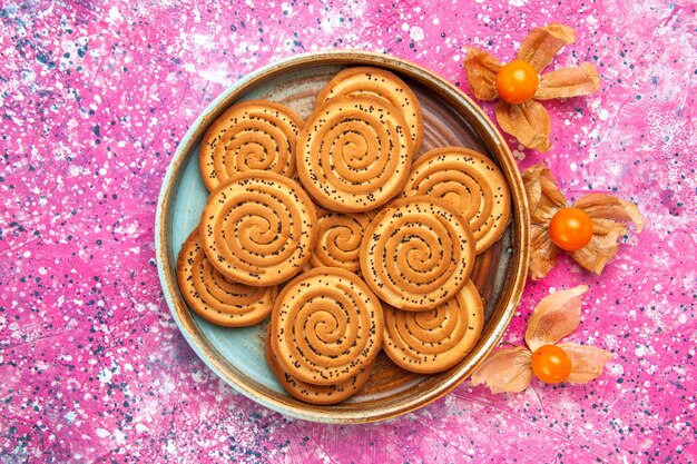 Vista superior de galletas dulces dentro de la placa sobre la superficie rosa