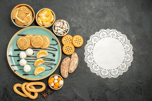 Vista superior de galletas dulces con galletas y caramelos sobre fondo gris