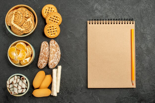 Vista superior de galletas dulces con galletas y frutas en un escritorio gris