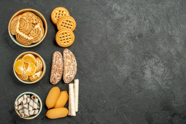 Vista superior de galletas dulces con galletas y frutas sobre fondo gris