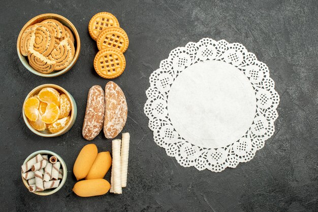 Vista superior de galletas dulces con galletas y frutas sobre fondo gris