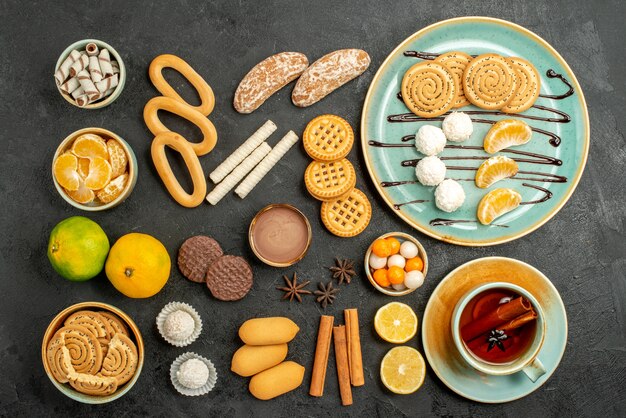 Vista superior de galletas dulces con galletas y té sobre fondo gris