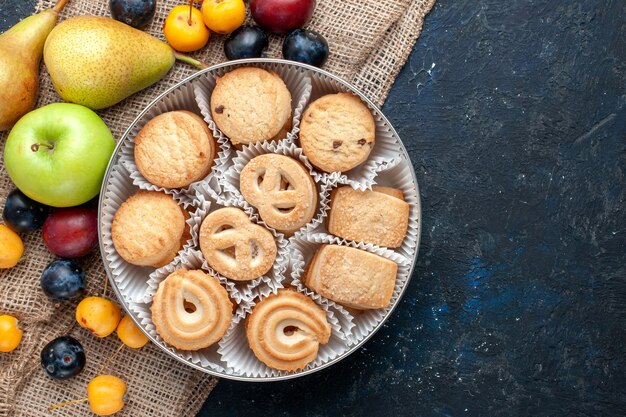 Vista superior de galletas dulces junto con diferentes frutas frescas en el escritorio azul oscuro galleta de fruta dulce dulce