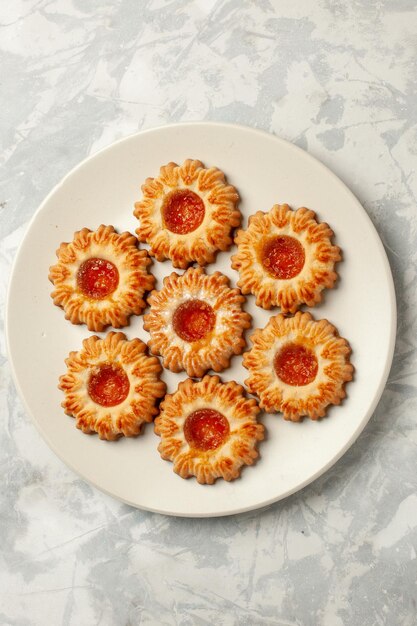 Vista superior de galletas dulces con mermelada de naranja sobre superficie blanca