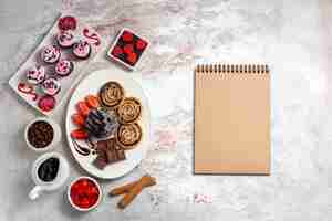 Foto gratuita vista superior de galletas dulces con pastel de chocolate sobre un fondo blanco galleta galleta pastel dulce azúcar té