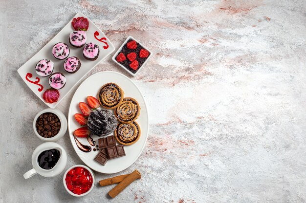 Foto gratuita vista superior de galletas dulces con pastel de chocolate sobre un fondo blanco galleta galleta pastel dulce azúcar té