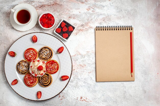 Vista superior de galletas dulces con pastelito y taza de té sobre un fondo blanco galleta dulce pastel de té galleta azúcar