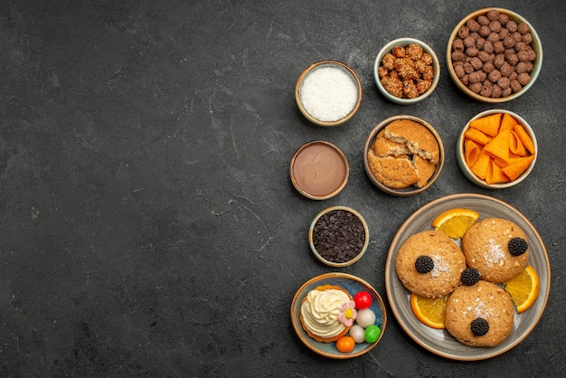 Vista superior de las galletas dulces con patatas fritas y rodajas de naranja en la superficie oscura fruti cookie biscuit sweet pie cake