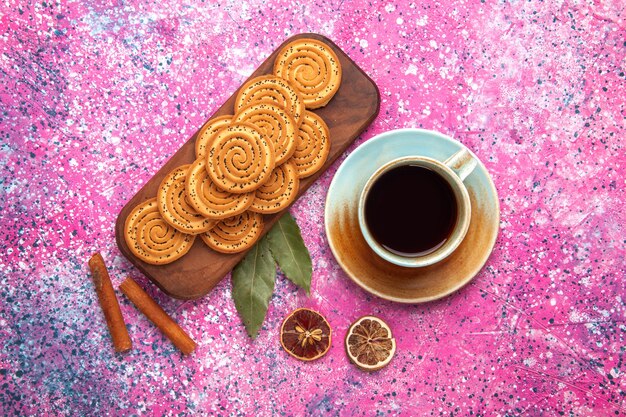 Vista superior de galletas dulces redondas forradas con té y canela en superficie rosa