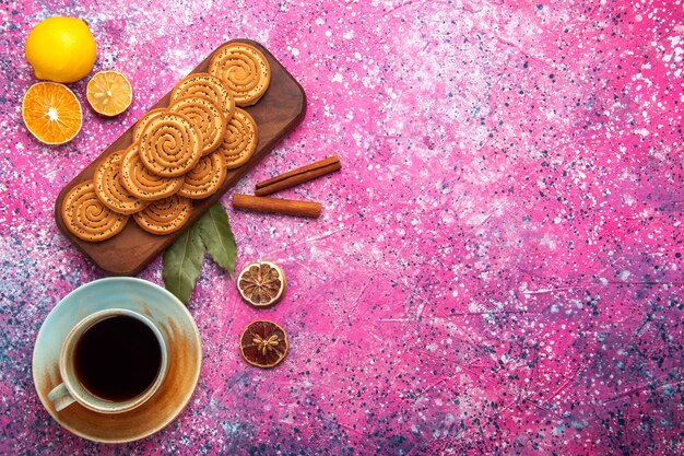 Vista superior de galletas dulces redondas forradas con té de limón y canela en la superficie rosa