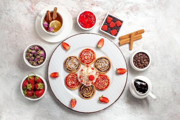 Vista superior de las galletas dulces con una taza de té sobre el fondo blanco dulce galleta de té de la galleta de la torta de azúcar