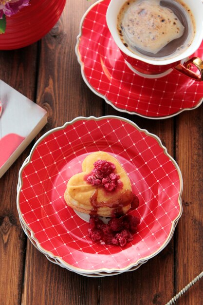 Vista superior de galletas en forma de corazón con frambuesas con una taza de café