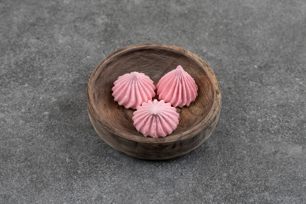 Vista superior de galletas de merengue rosa fresco en un tazón de madera