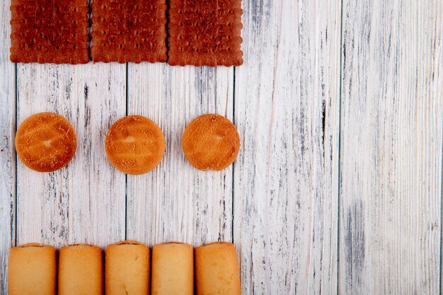 Vista superior Galletas con mermelada y galletas de chocolate a la izquierda con espacio de copia sobre fondo blanco de madera