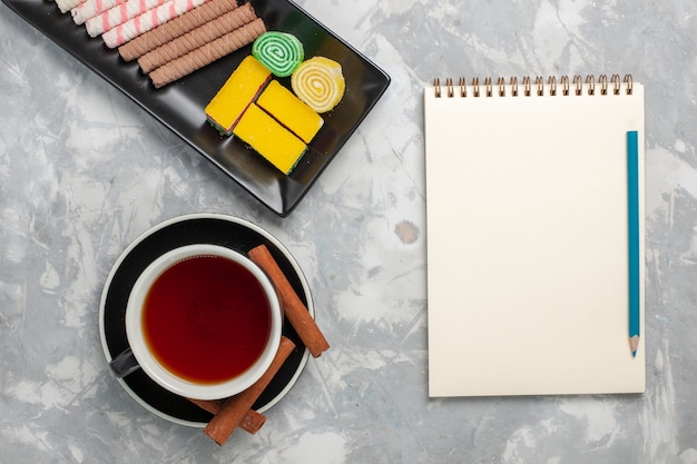 Vista superior de las galletas de pipa con mermelada y una taza de té sobre fondo blanco pastel de pastel dulce de azúcar de galleta de galleta