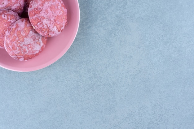 Vista superior de galletas rosadas caseras en un tazón rosa.