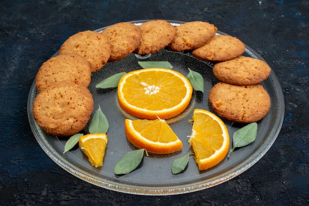Una vista superior de las galletas con sabor a naranja con rodajas de naranja fresca dentro de la placa sobre el fondo oscuro galleta de azúcar de galleta
