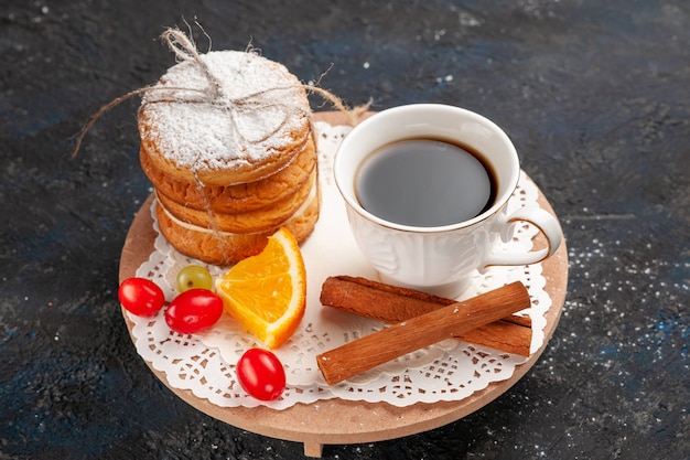 Vista superior de las galletas sándwich con relleno de crema junto con canela y café en la superficie oscura.