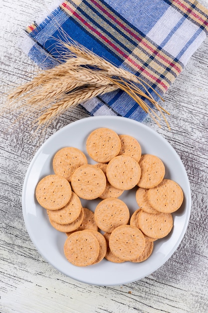 Foto gratuita vista superior de galletas con trigo sobre tela en blanco vertical de madera