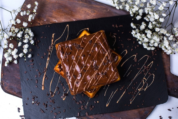 Vista superior de gofre belga con chocolate sobre una plancha de madera