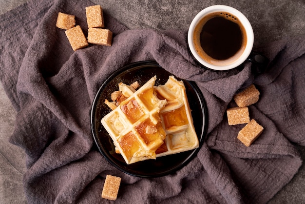 Foto gratuita vista superior de gofres cubiertos de miel con taza de café