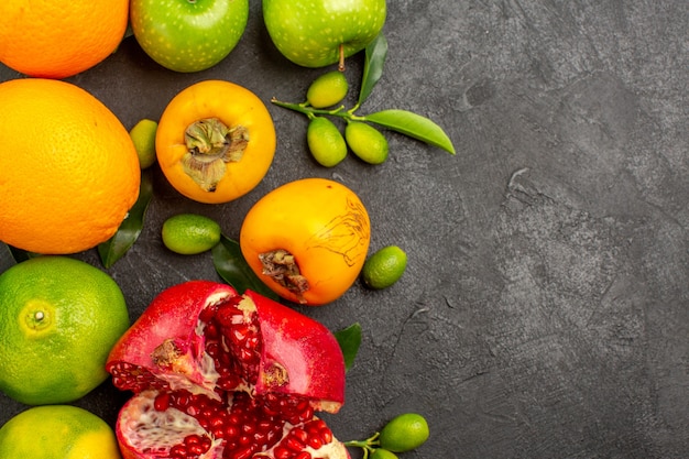 Vista superior de granada fresca con manzanas y mandarinas sobre una superficie oscura de color de fruta madura