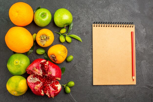 Vista superior de granadas frescas con manzanas y otras frutas en el color de la fruta madura de la superficie oscura