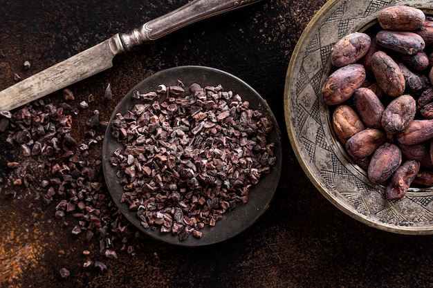 Vista superior de granos de cacao molidos en un plato con cuchillo y granos de cacao