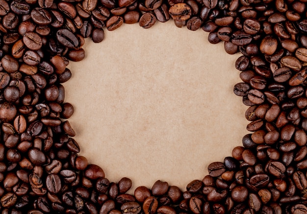 Vista superior de los granos de café círculo sobre fondo de textura de papel marrón