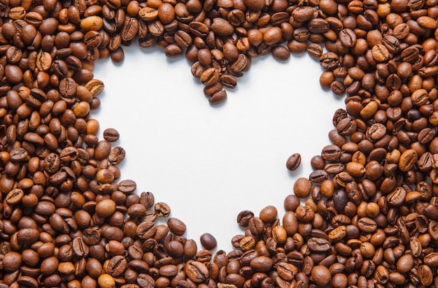 Vista superior de granos de café con forma de corazón vacío sobre fondo blanco. horizontal