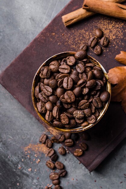 Vista superior de los granos de café en taza sobre tabla de cortar con canela