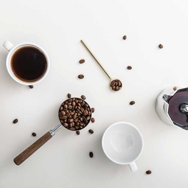 Vista superior de los granos de café en taza con tetera y cuchara