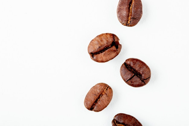 Vista superior de granos de café tostado aislado sobre fondo blanco con espacio de copia