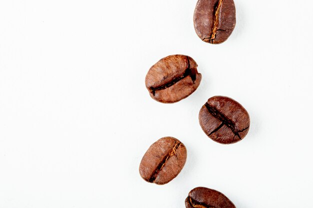 Vista superior de granos de café tostado aislado sobre fondo blanco con espacio de copia