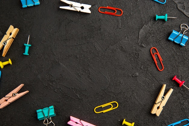 Vista superior de grapas de colores con pinzas para la ropa sobre fondo oscuro foto de color de lavandería escolar