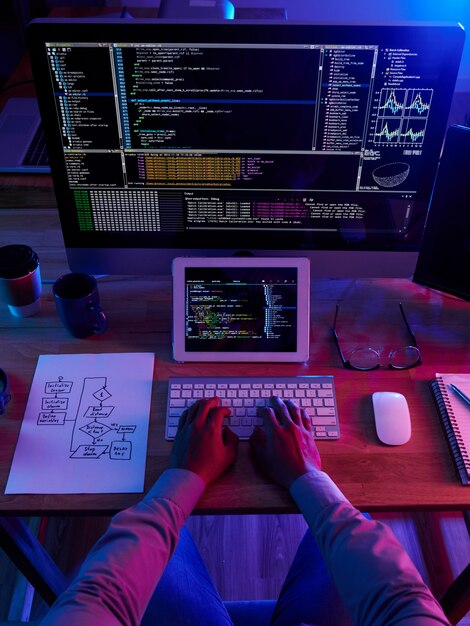 Vista superior de un hacker irreconocible realizando un ciberataque por la noche
