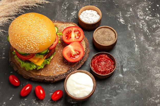 Vista superior hamburguesa de carne con queso con condimentos en el escritorio oscuro sándwich de pan de comida rápida