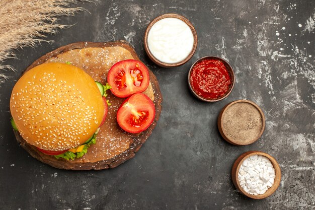 Vista superior hamburguesa de carne con queso con condimentos en las papas fritas de carne de sándwich de pan de superficie oscura