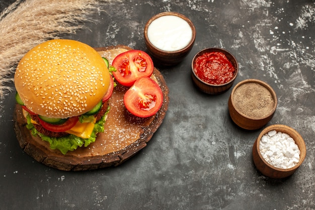 Vista superior hamburguesa de carne con queso con condimentos en las papas fritas de carne de sándwich de pan de superficie oscura