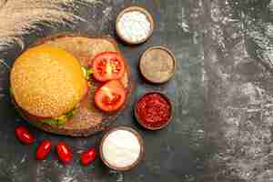 Foto gratuita vista superior hamburguesa de carne con queso con condimentos en superficie oscura sándwich de pan de comida rápida