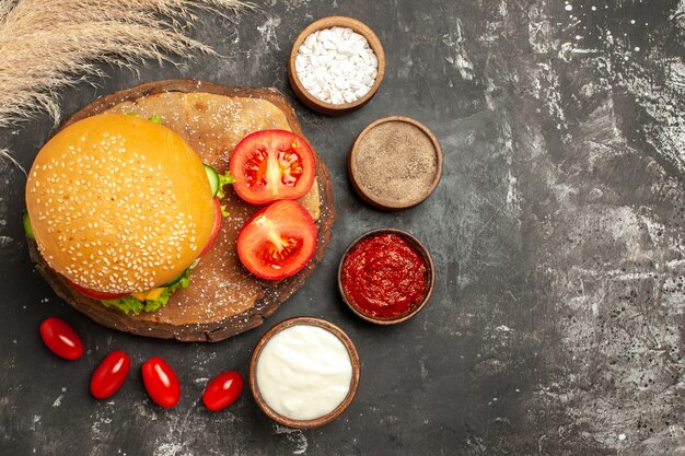 Vista superior hamburguesa de carne con queso con condimentos en superficie oscura sándwich de pan de comida rápida