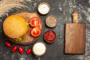 Foto gratuita vista superior hamburguesa de carne con queso con condimentos en superficie oscura sándwich de pan de comida rápida