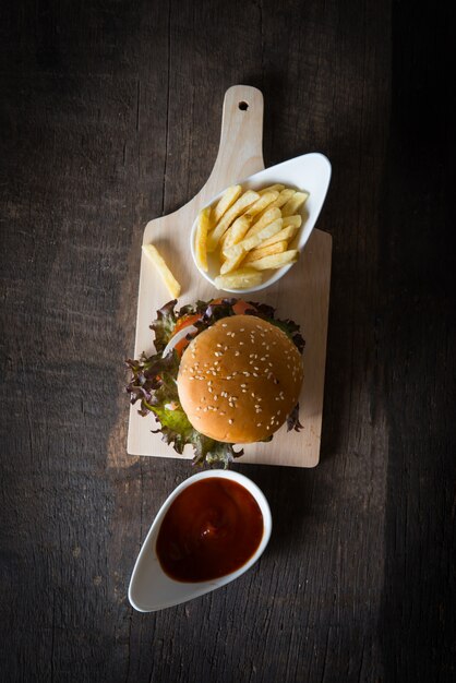 Vista superior de hamburguesa casera rústica y patatas fritas con salsa de tomate.