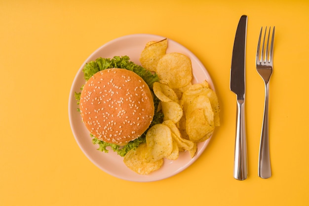 Foto gratuita vista superior hamburguesa y papas fritas con cubiertos