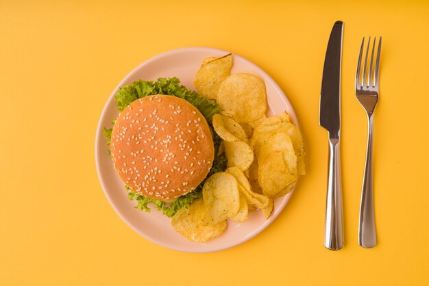 Vista superior hamburguesa y papas fritas con cubiertos