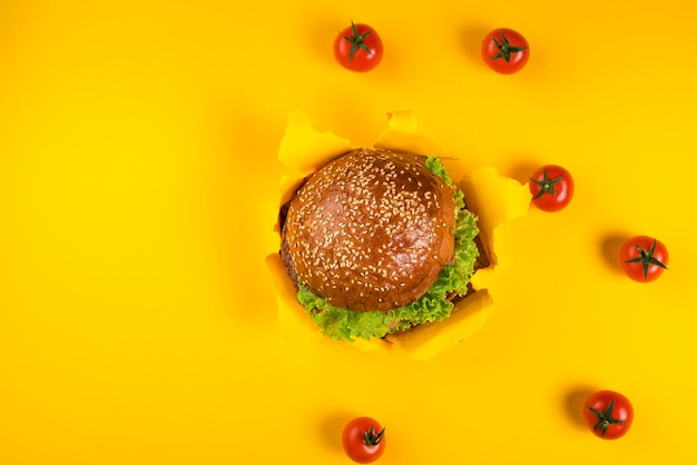 Vista superior hamburguesa de ternera rodeada de tomates cherry