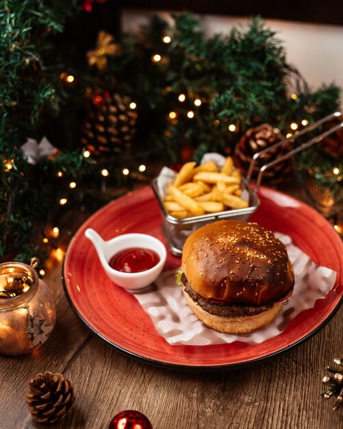 Vista superior de hamburguesa de ternera servida con papas fritas ketchup oreja decoraciones navideñas