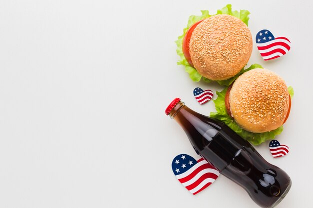 Vista superior de hamburguesas con banderas y botella de refresco