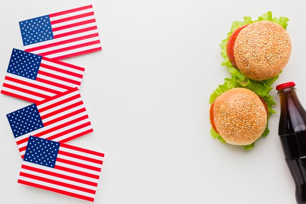 Vista superior de hamburguesas con botella de refresco y banderas americanas